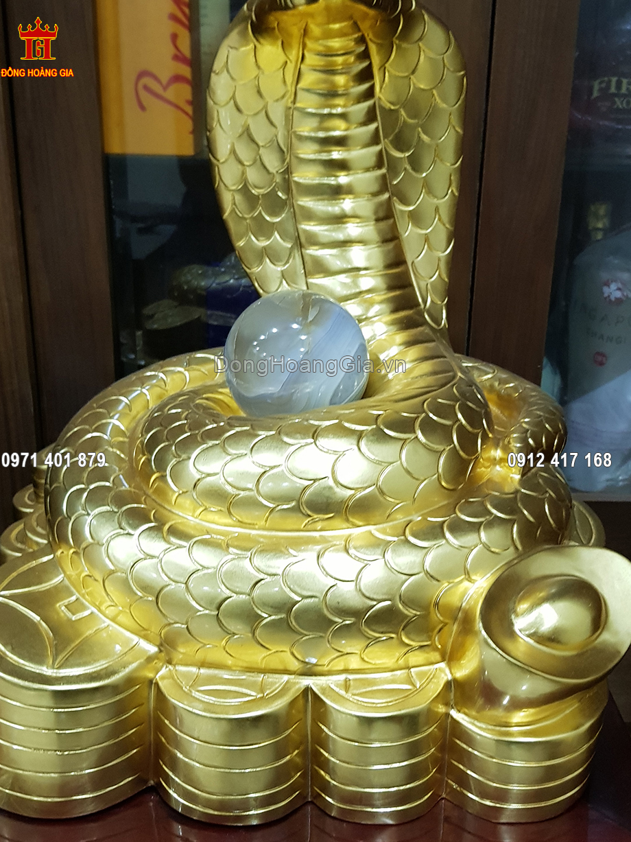 Hình tượng rắn khắc họa rõ nét và tỉ mỉ bằng đồng vàng đang ngồi cuộn tròn trên nén vàng với ý nghĩa mang lại tài lộc, may mắn cho gia chủ